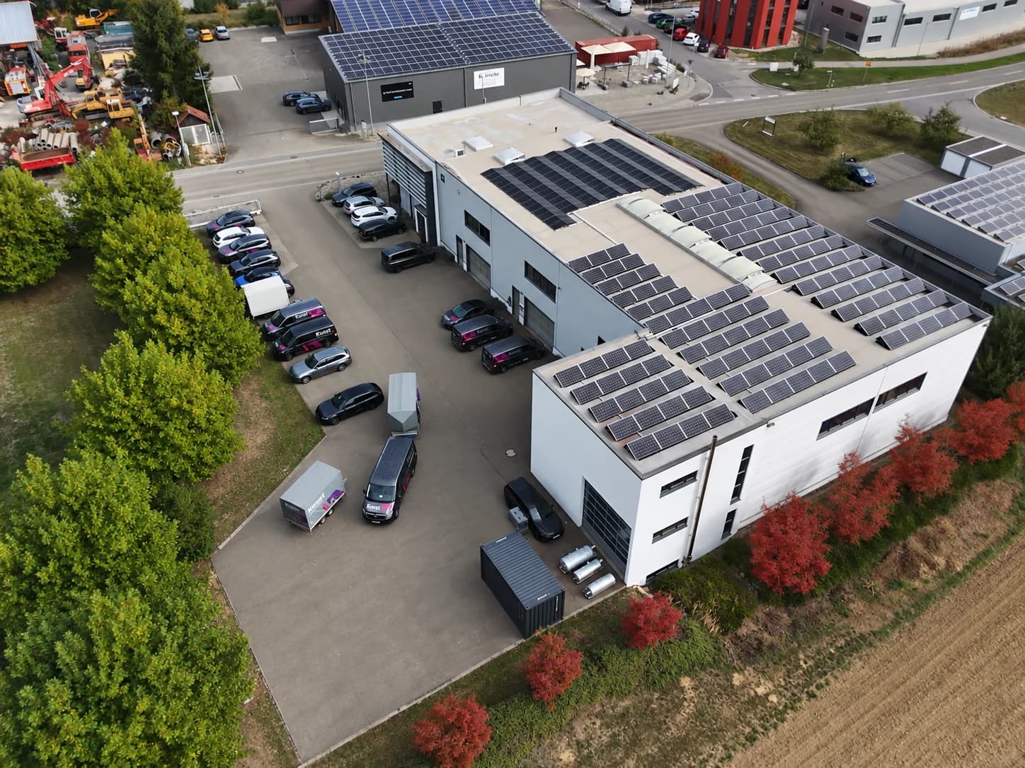 Luftaufnahme des Firmengebäudes von Kunst Drucklufttechnik mit Solarmodulen auf dem Flachdach und Servicefahrzeugen auf dem Hof
